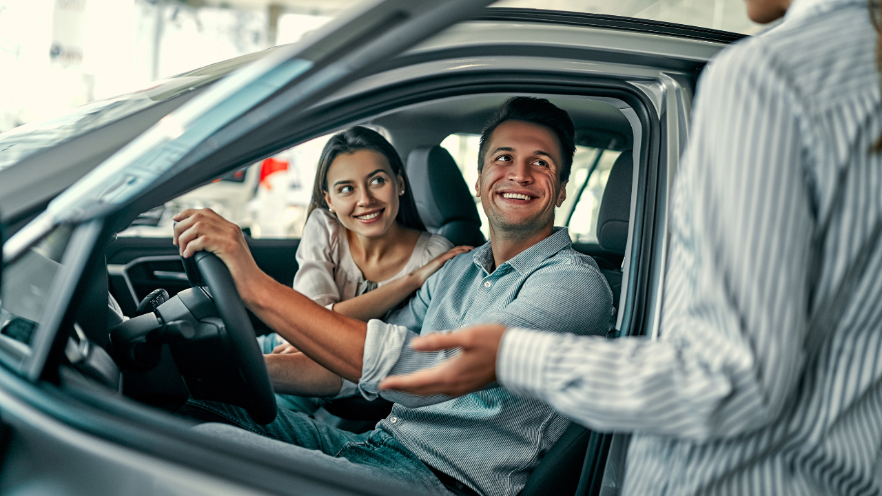 Un représentant de concessionnaire remettant les clés d’une voiture à une cliente souriante